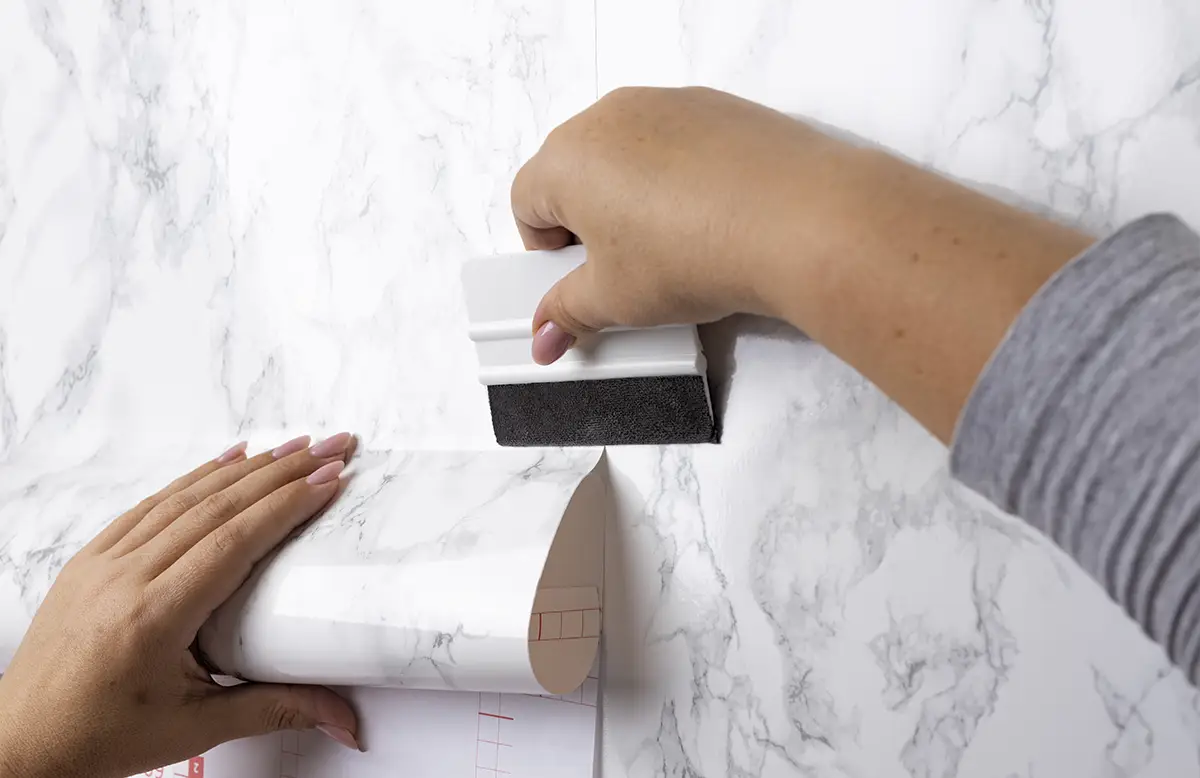 Essential tools for easy and effective wallpaper removal including scraper, sponge, and scoring tool