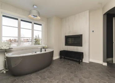Luxury bathroom renovation in a modern London home with freestanding bath, walk in shower, marble effect tiles and warm feature lighting.