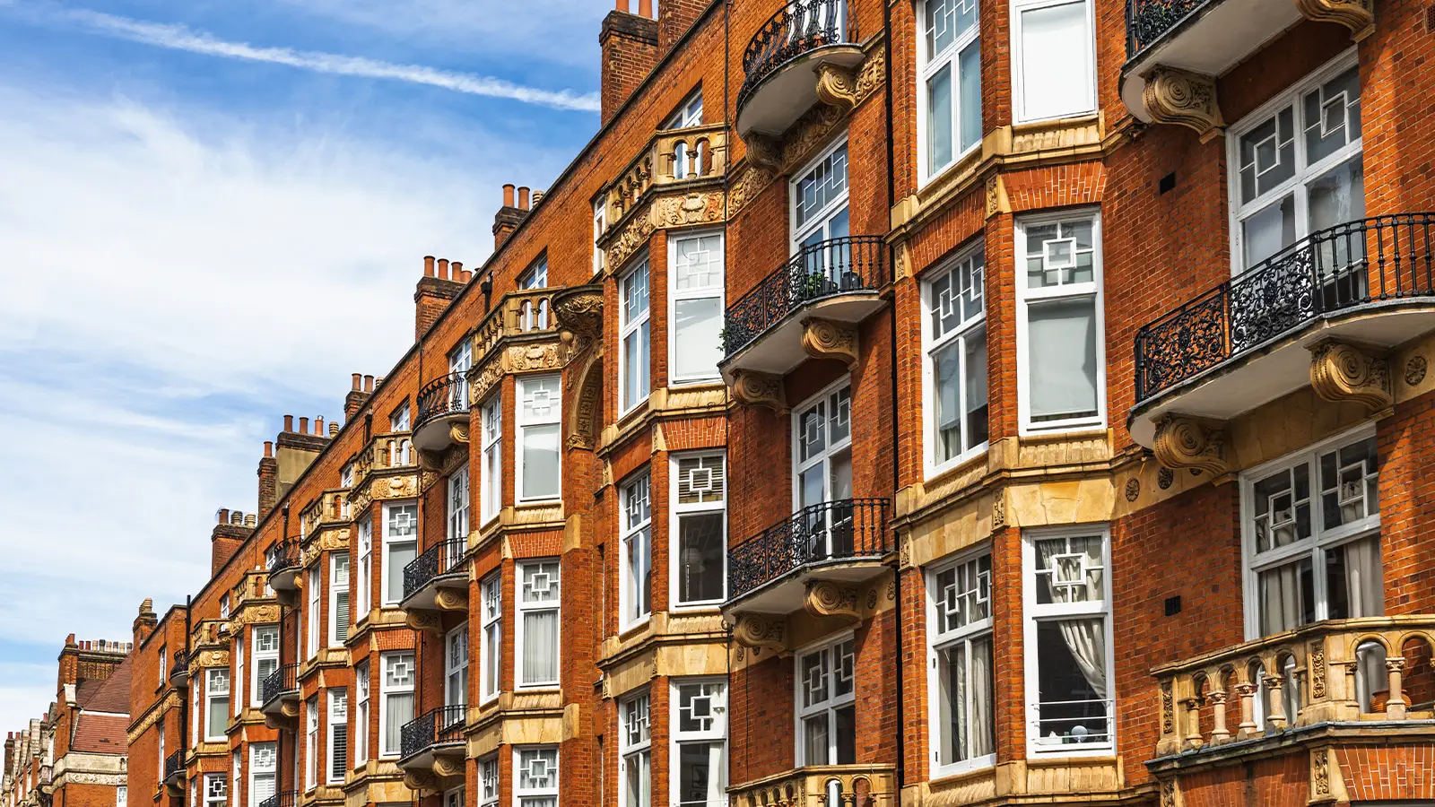 Red brick Edwardian mansion block flats with stone banding and iron balconies in Kensington, London