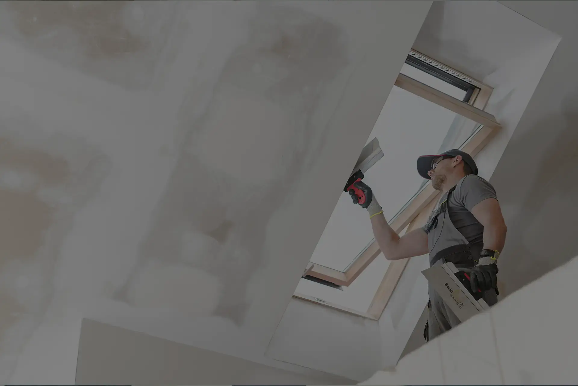 Beck's Homes UK tradesman plastering around a skylight window during a loft refurbishment
